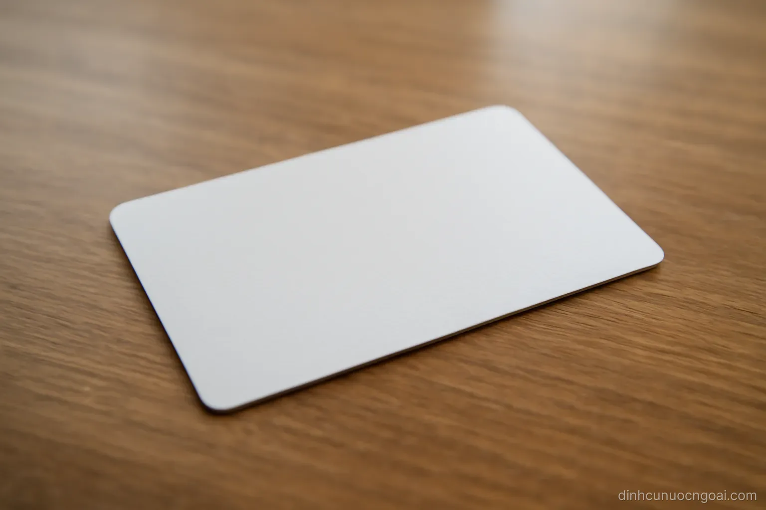 a plain plastic card lying face up on a desk with an embossed surface and no visible printed characters
